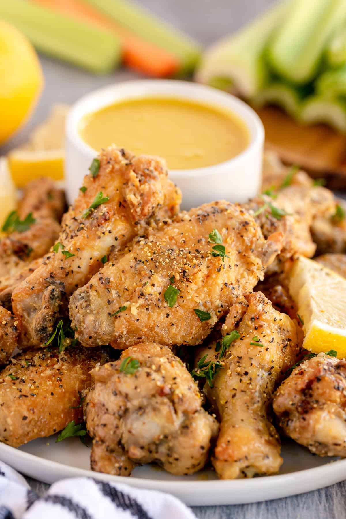 Lemon pepper wings on a white platter with mustard dipping sauce.