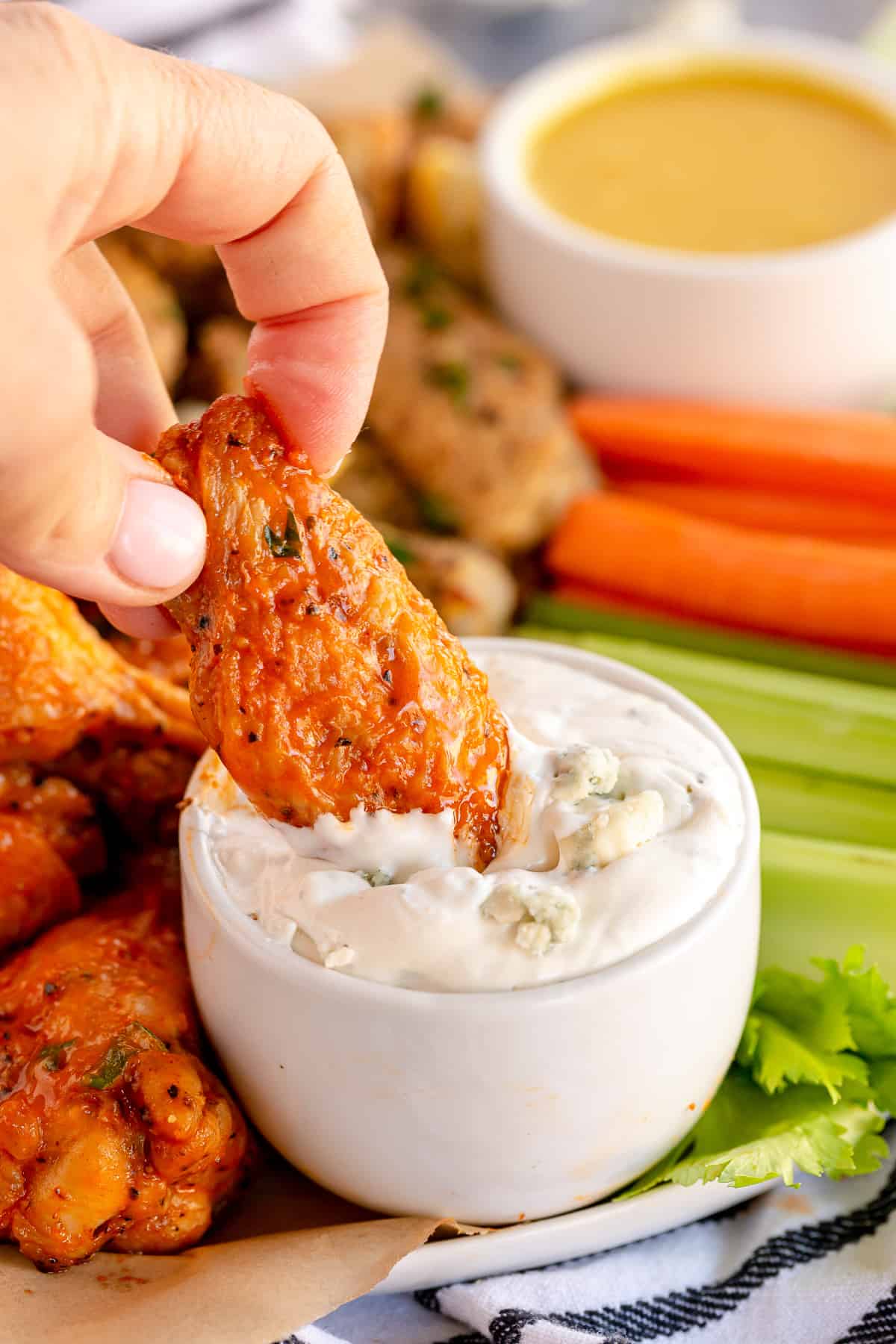 An air fryer buffalo chicken wing dipping into blue cheese ranch dip.