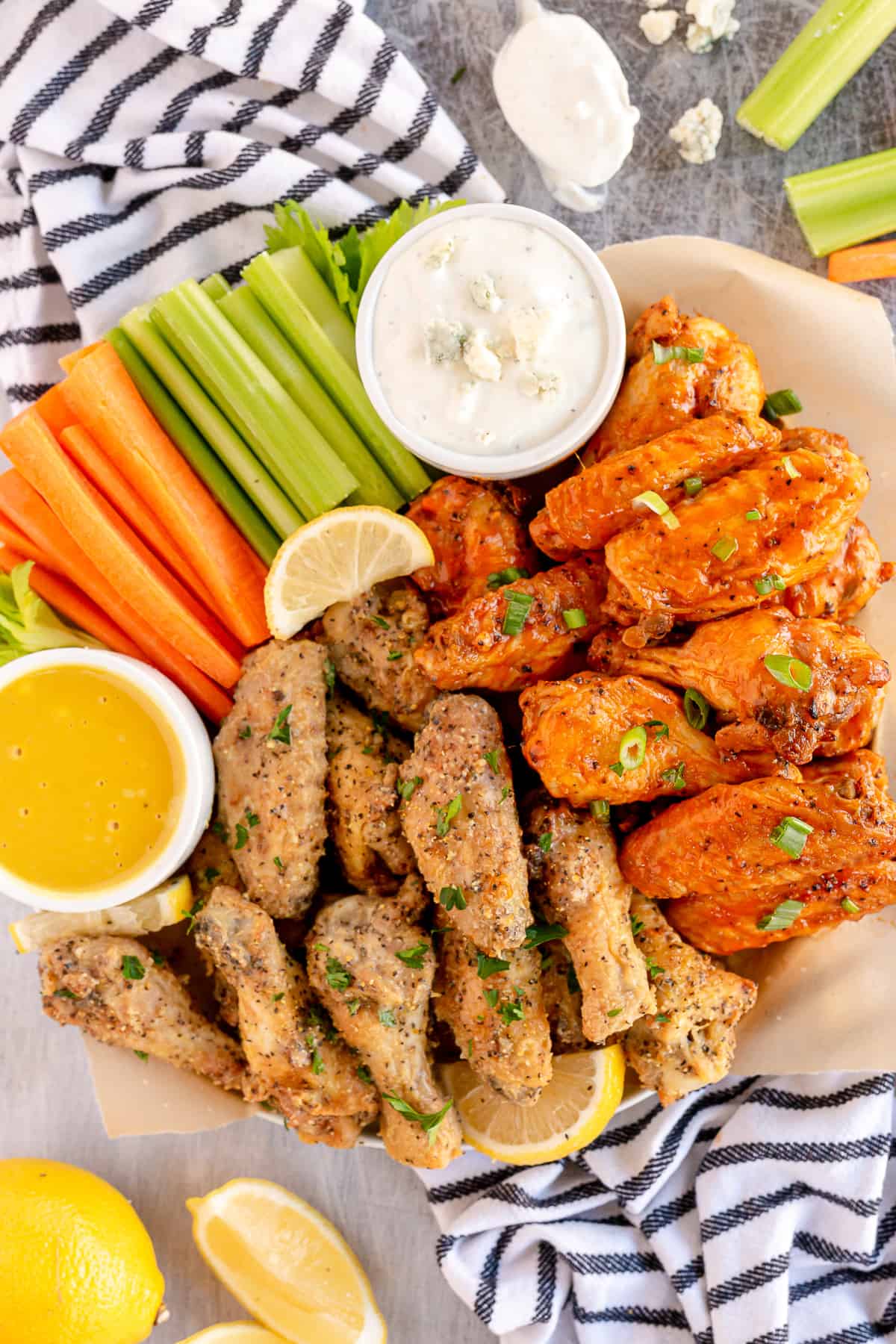 A platter of buffalo and lemon pepper wings with celery and carrot sticks.