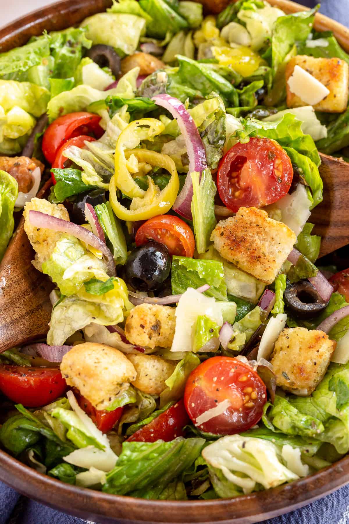 A close up of a salad with tomatoes, olives, croutons and parmesan.