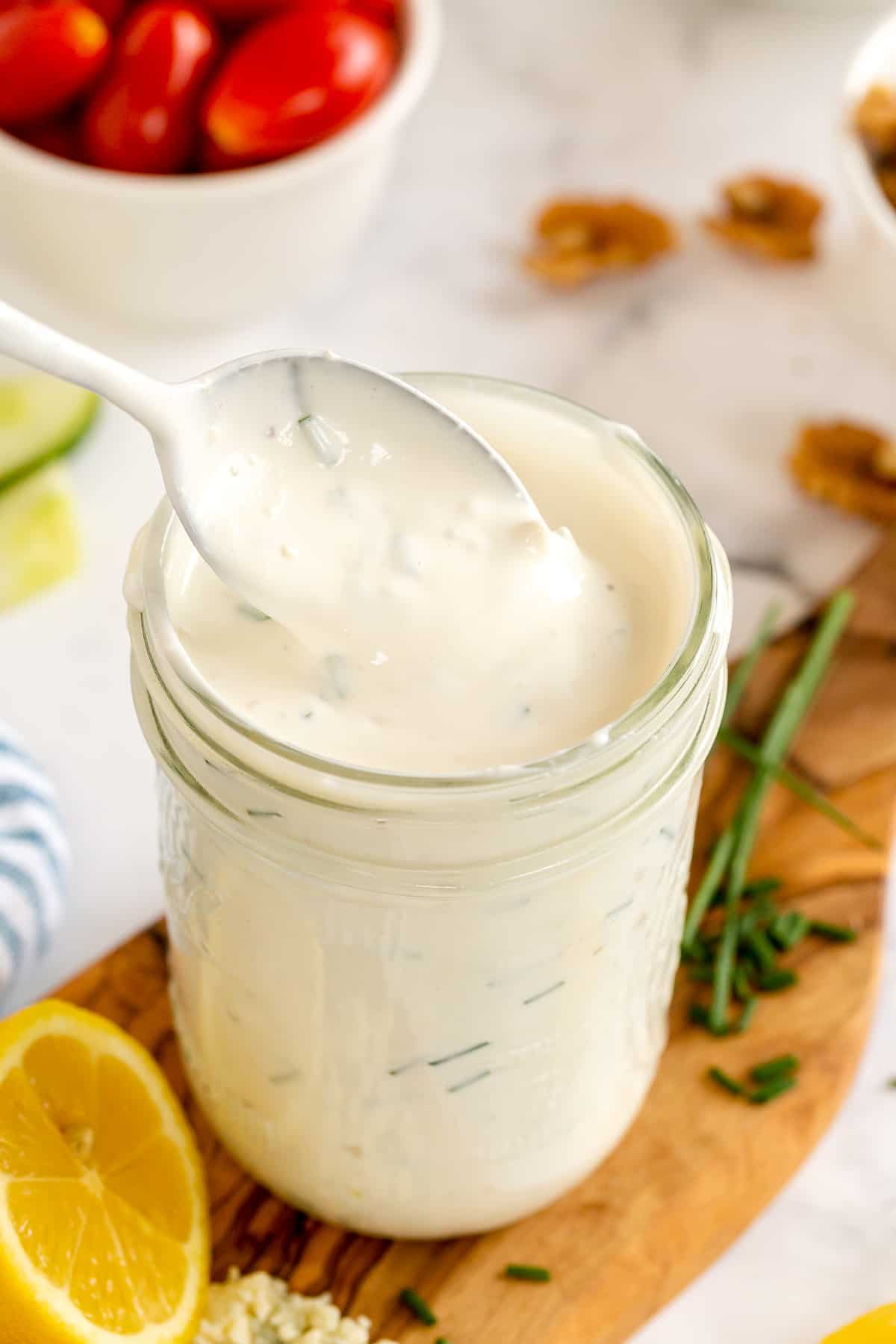 A spoon lifts out of a mason jar filled with blue cheese dressing.