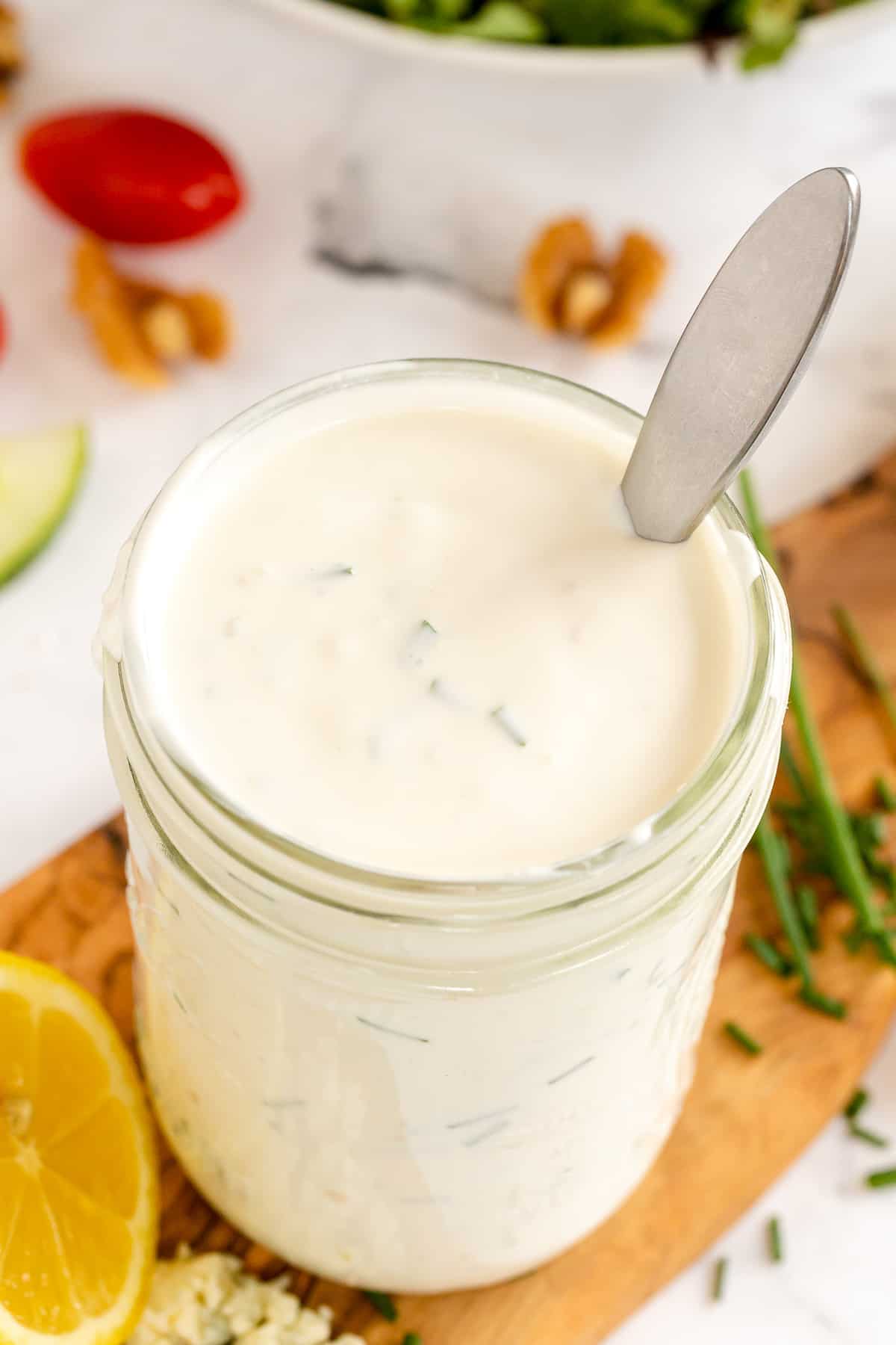 A spoon rests in a mason jar filled blue cheese dressing.