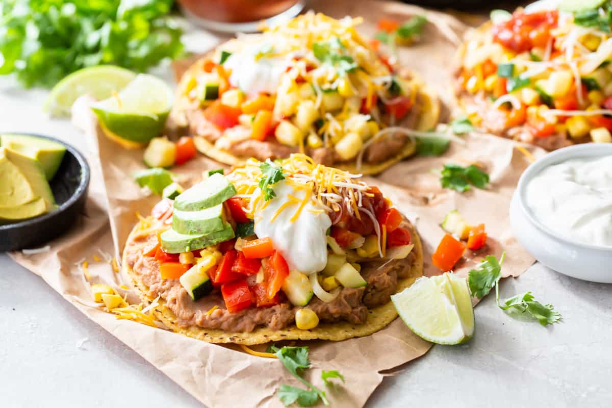 A side view of a tostada with sauteed vegetables on parchment paper.