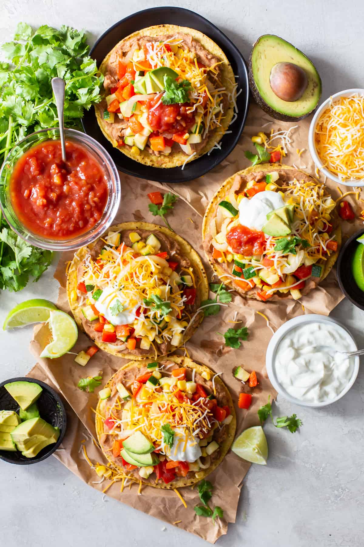 An over the top shot of four veggie tostadas on parchment paper.