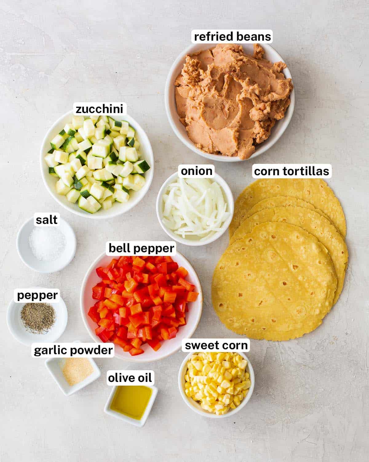 Tortillas, zucchini, bell pepper, corn and other ingredients for Veggie Tostadas with overlay text.