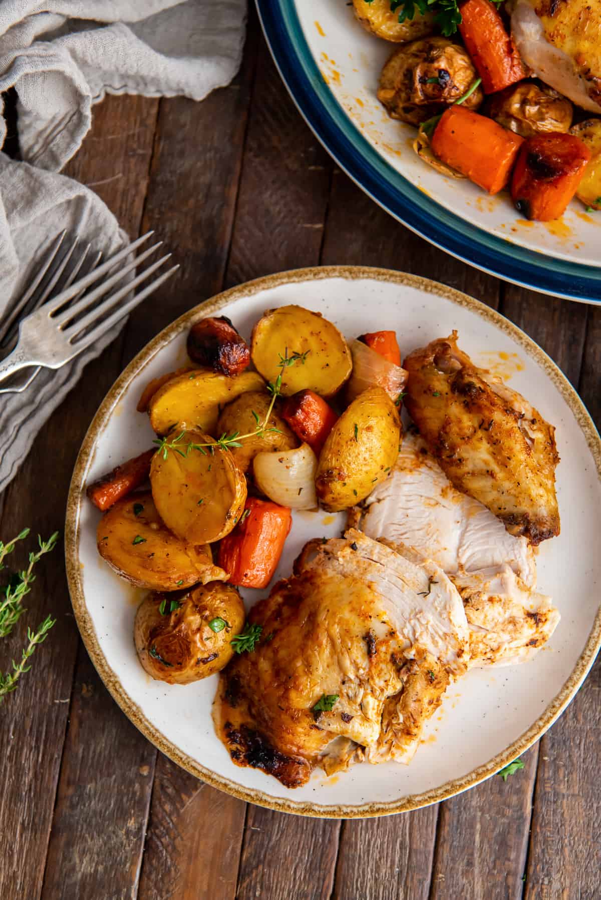 Slices of roasted chicken on a plate with carrots, potatoes, and onions.