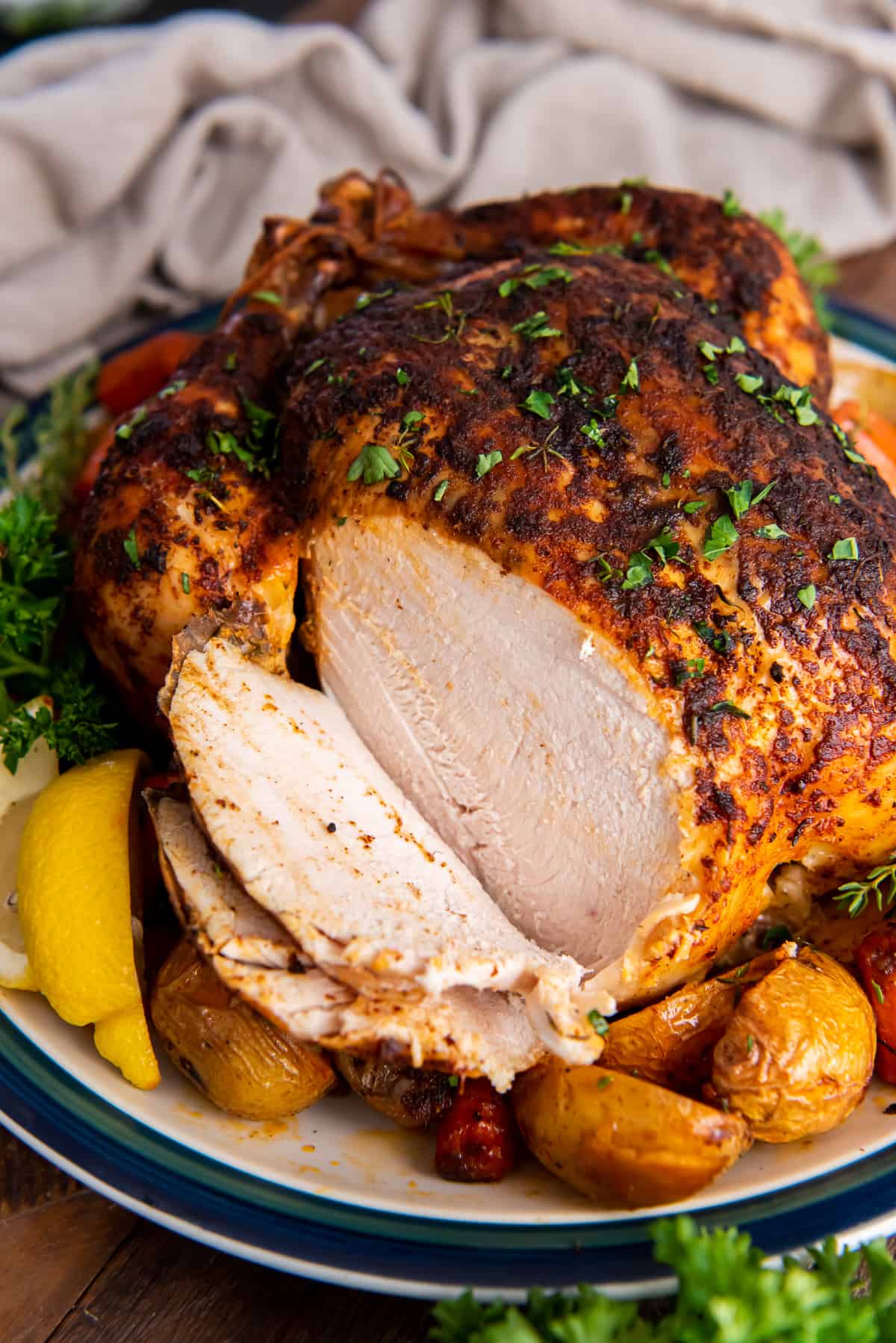 A crispy roast chicken with part of the breast meat sliced.