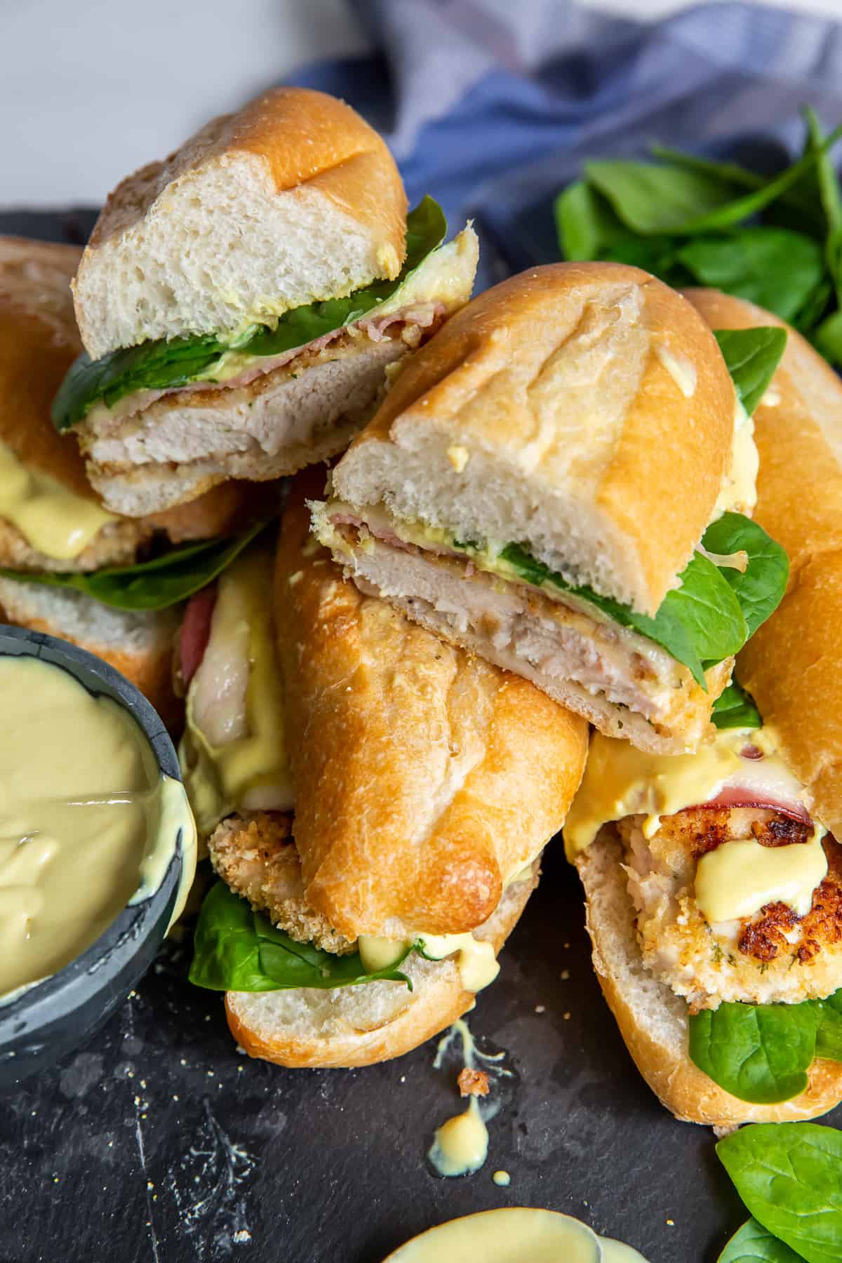 Breaded chicken sandwiches with honey mustard sauce piled up on a black surface.