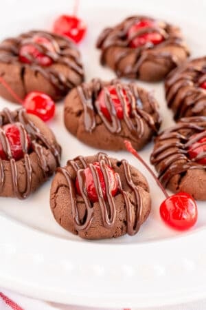 Chocolate Covered Cherry Cookies on a white plate with maraschino cherries.