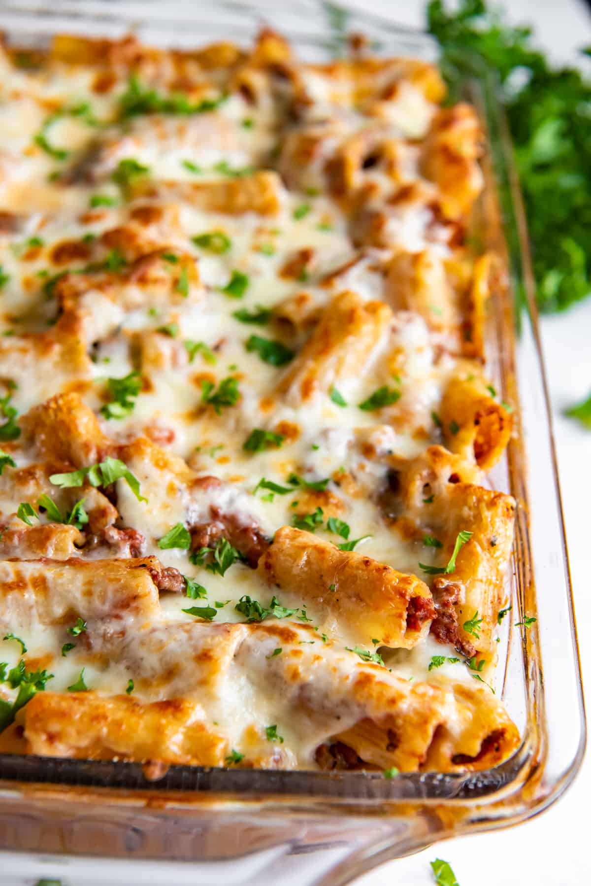 A casserole dish filled with cheesy baked rigatoni with meat sauce.