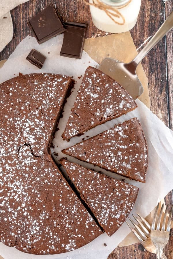 A spatula tucked under a slice of French Chocolate Cake.