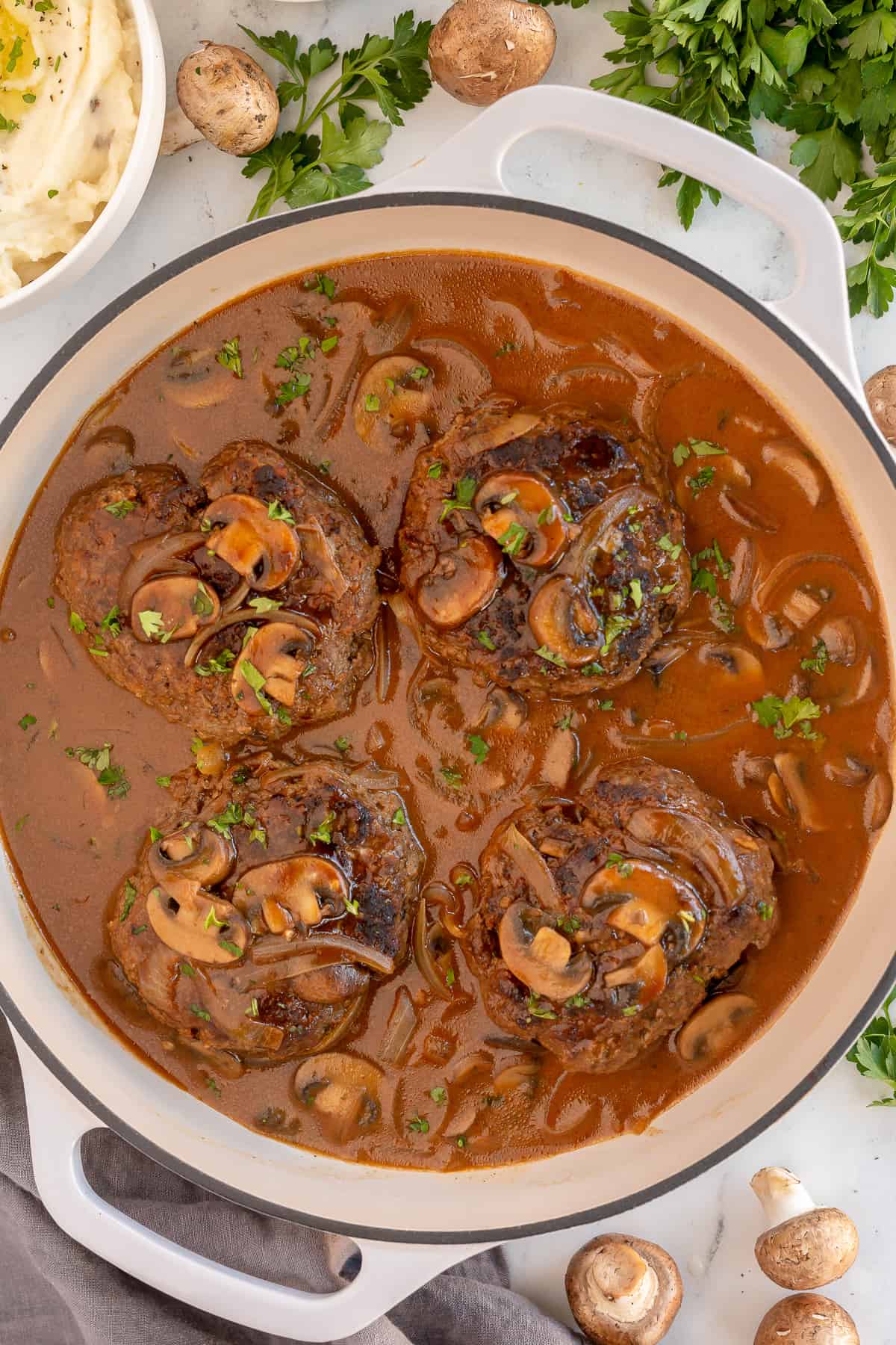 An over the top shot of a skillet of Salisbury steak with mushroom onion gravy.