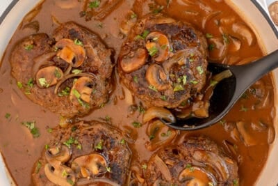 Salisbury steaks in a skillet with mushroom gravy.