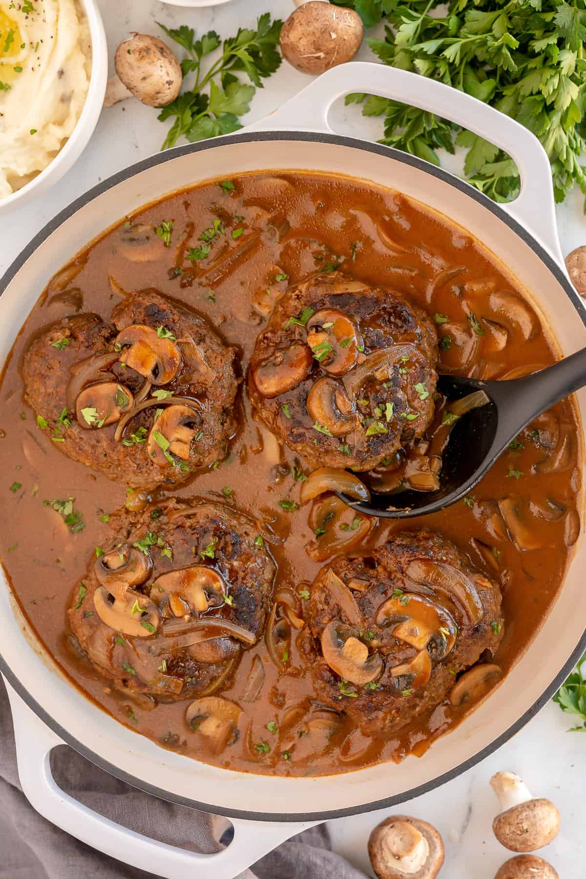 Salisbury steaks in a skillet with mushroom gravy.