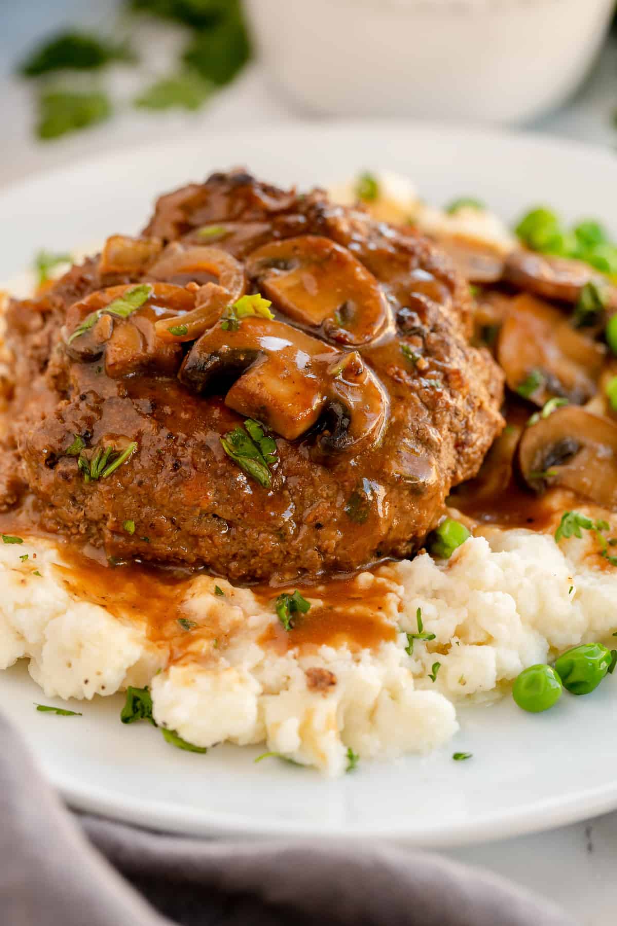 A close up of Salisbury steak on mashed potatoes.