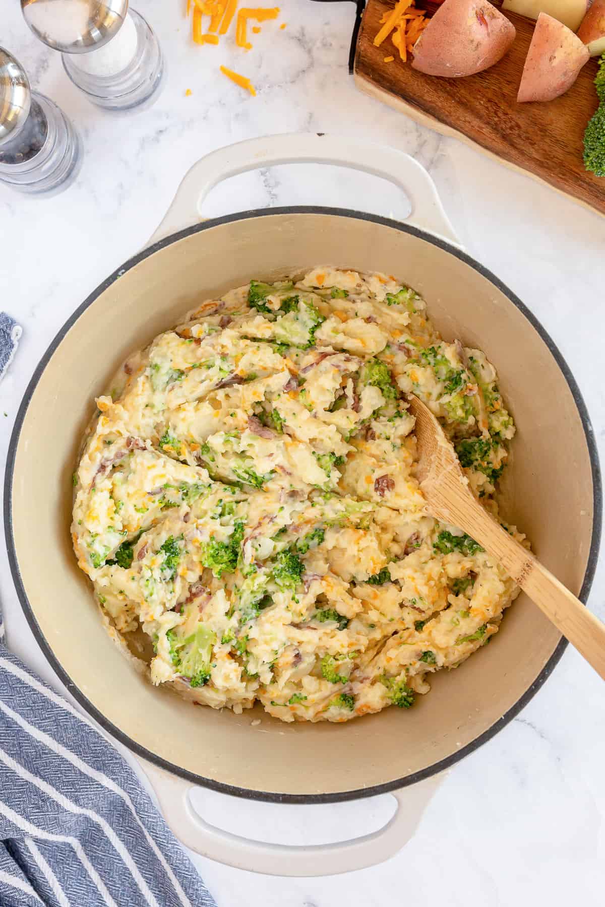 Broccoli cheese mashed potatoes in a pot with a wooden spoon.