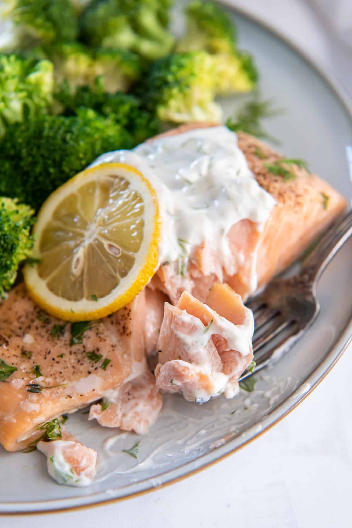 A fork with a bite of salmon on a plate.