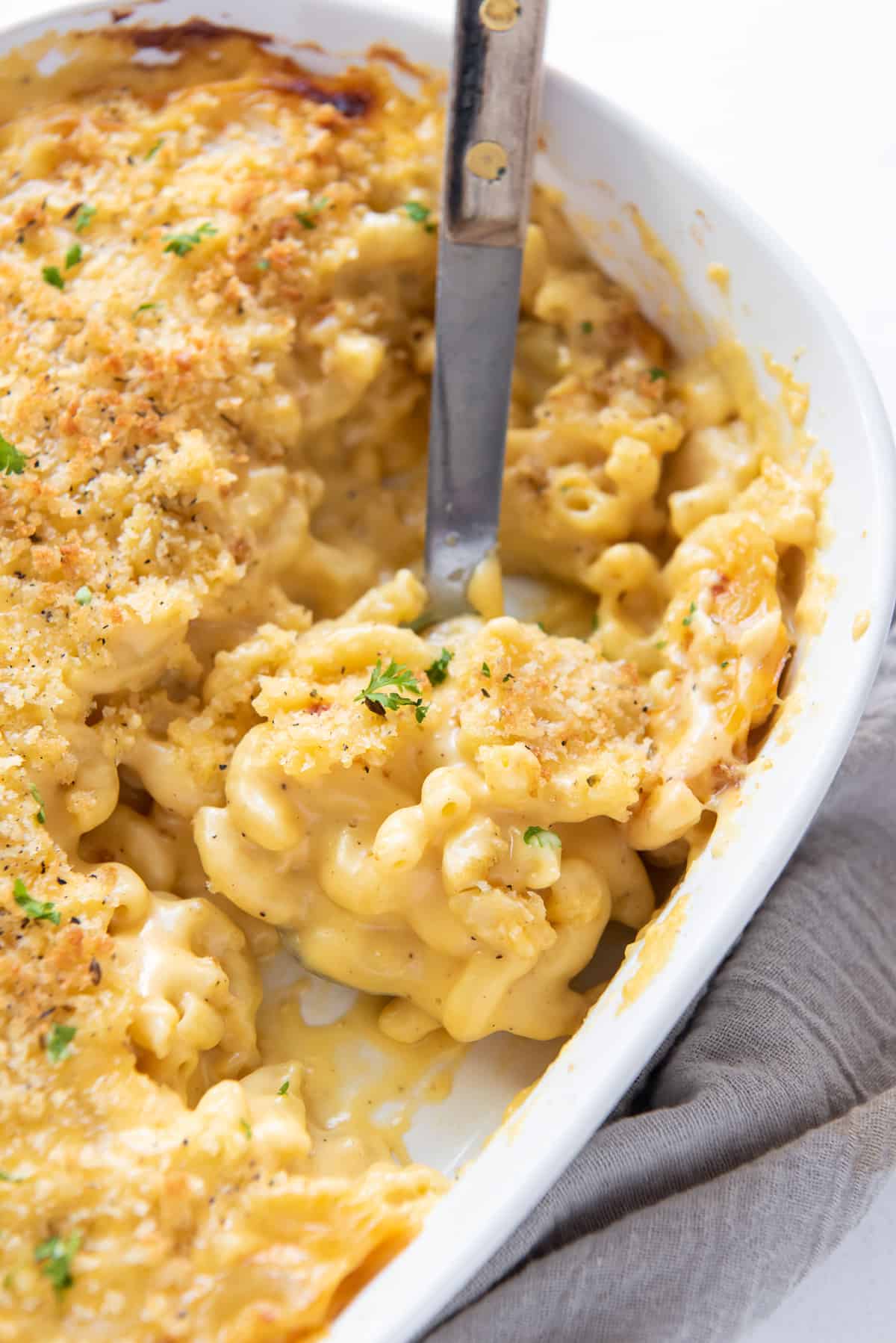 A spoon scoops macaroni and cheese from a baking dish.