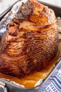 A glazed spiral sliced ham in a roasting pan.