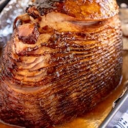 A glazed spiral sliced ham in a roasting pan.