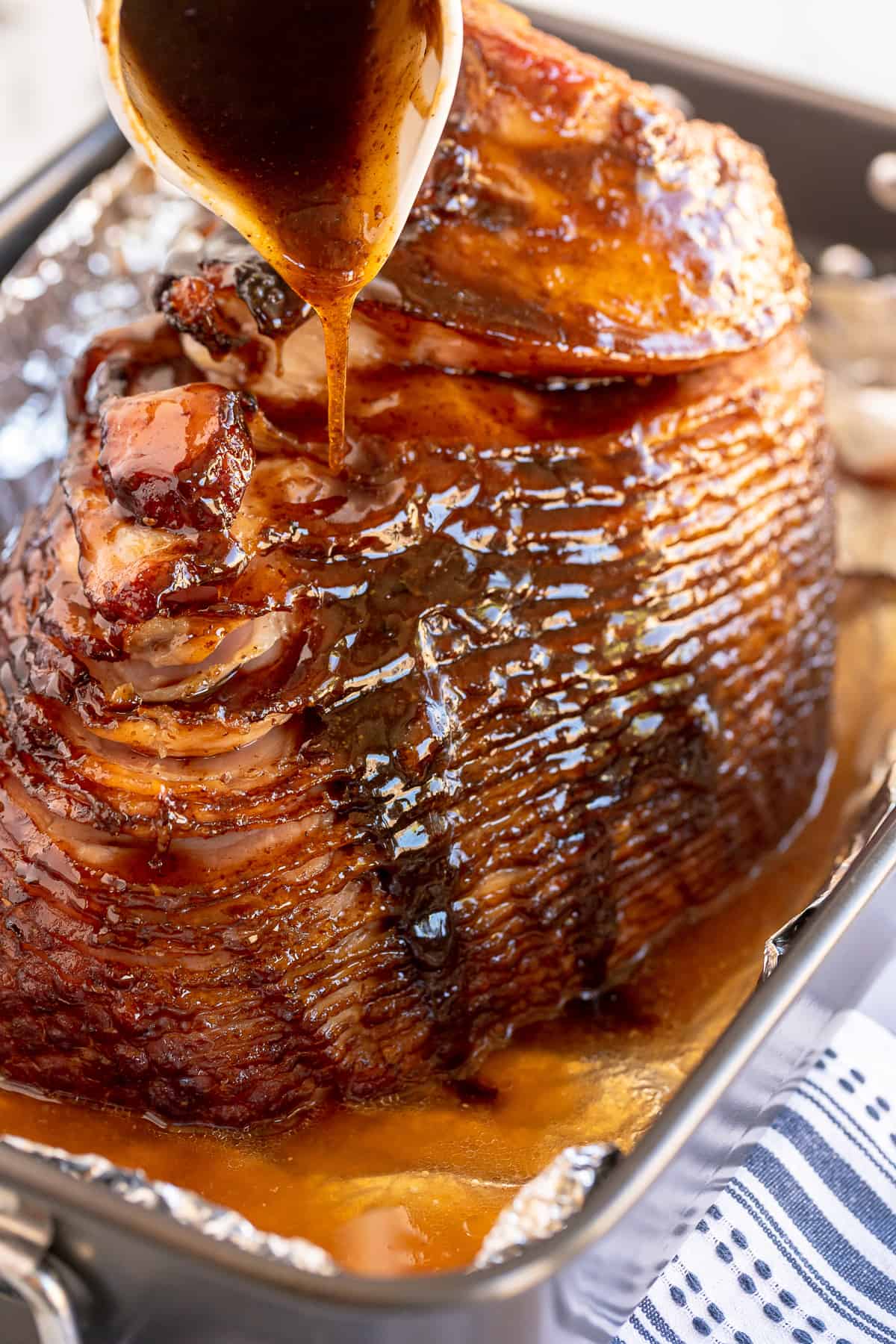 Maple glaze is poured over a baked ham.