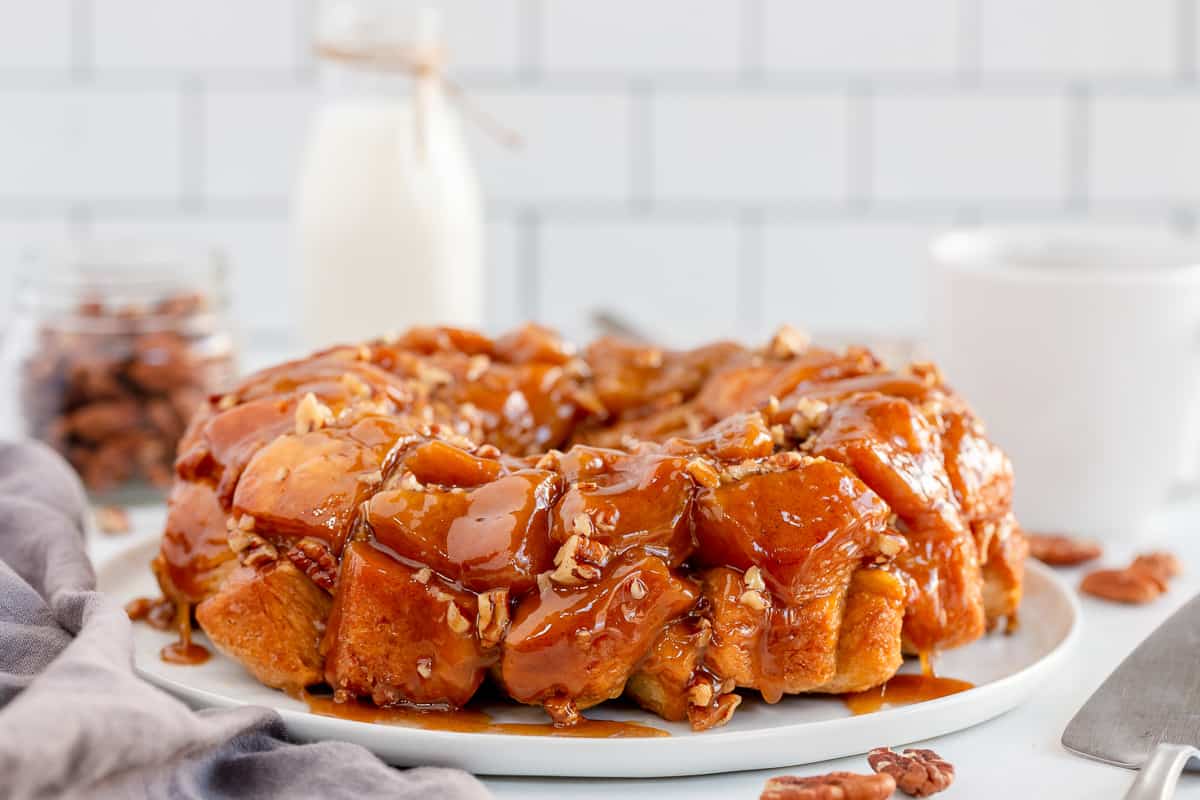 Monkey bread with pecans on a plate with a bottle of milk behind it.