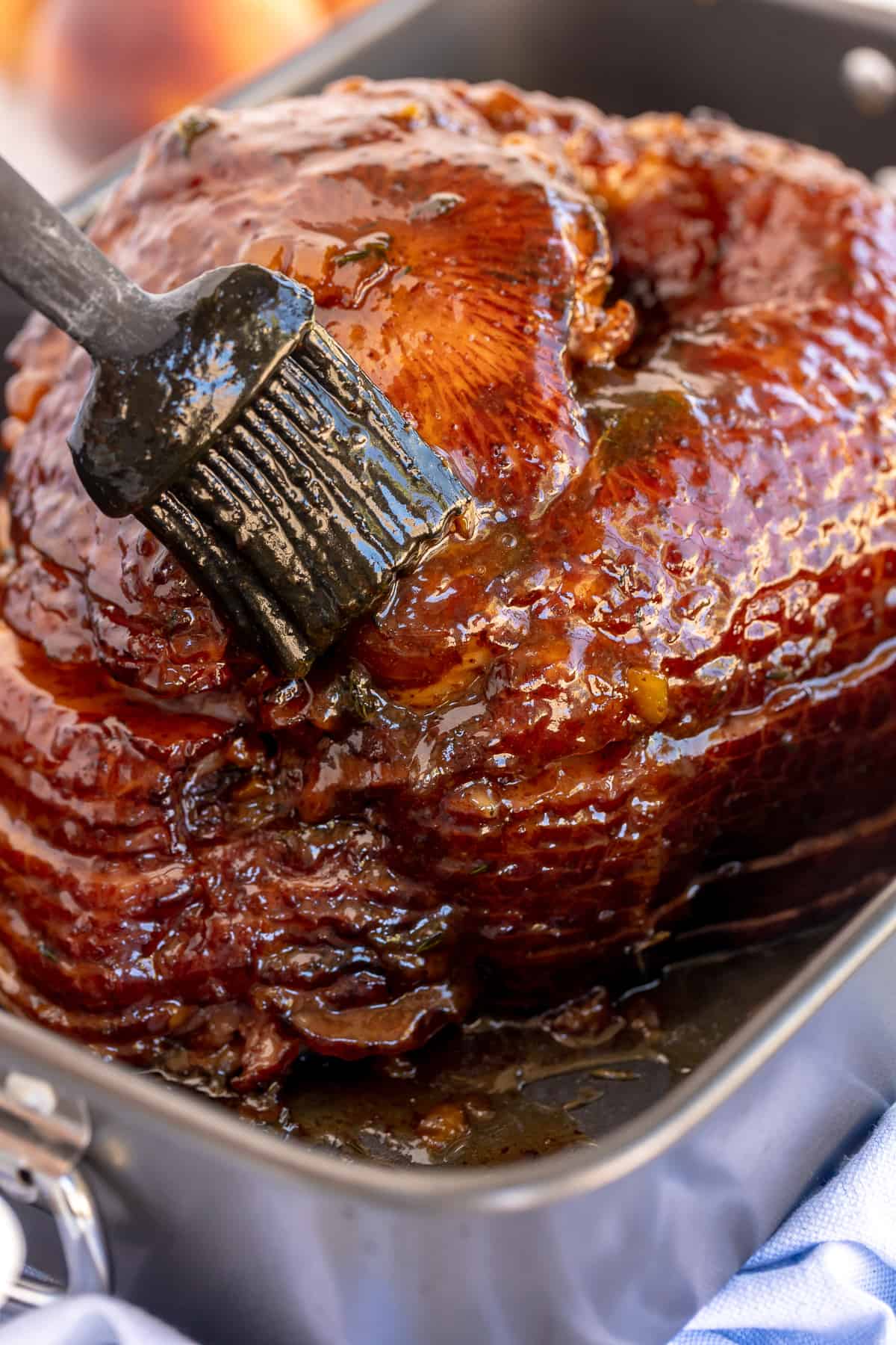 A spiral ham is brushed with glaze.