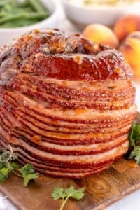 A spiral ham with peach thyme glaze on a wood board.