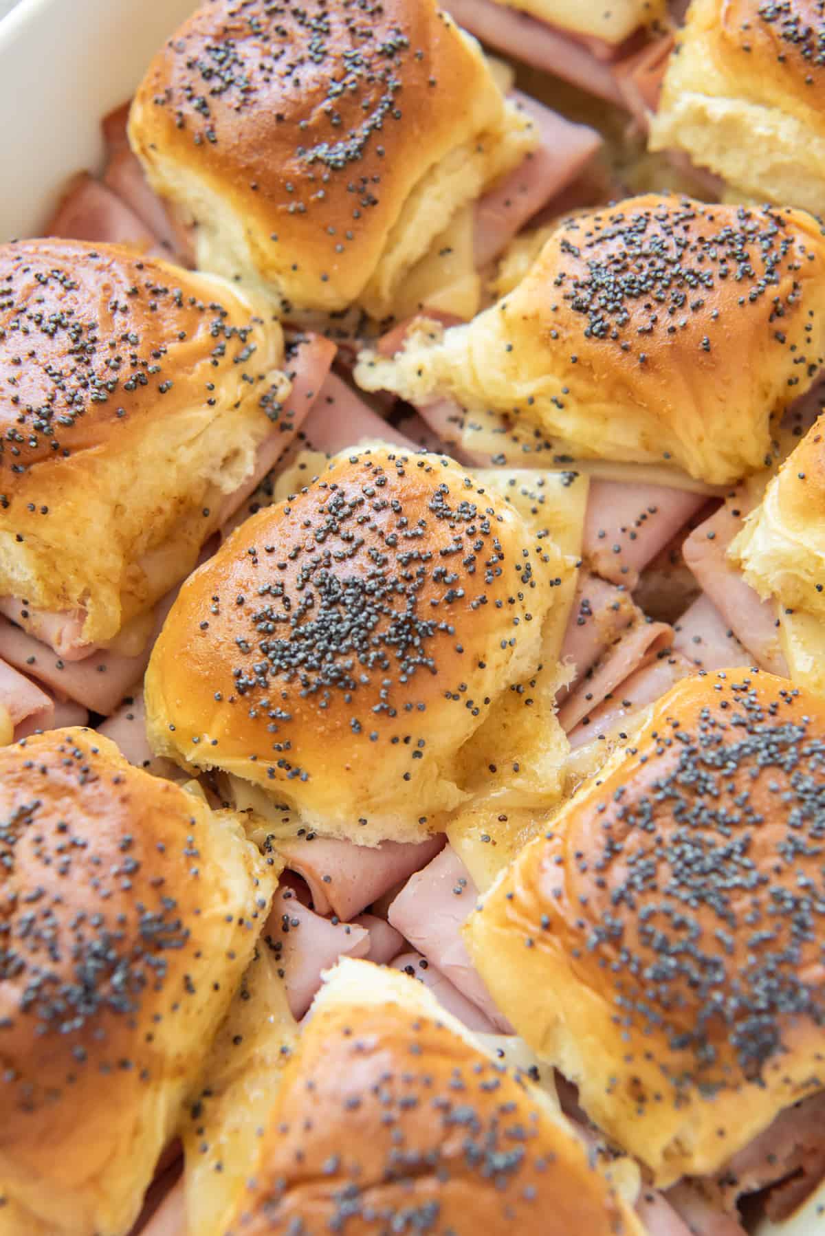 A close up of sliders topped with poppy seeds.