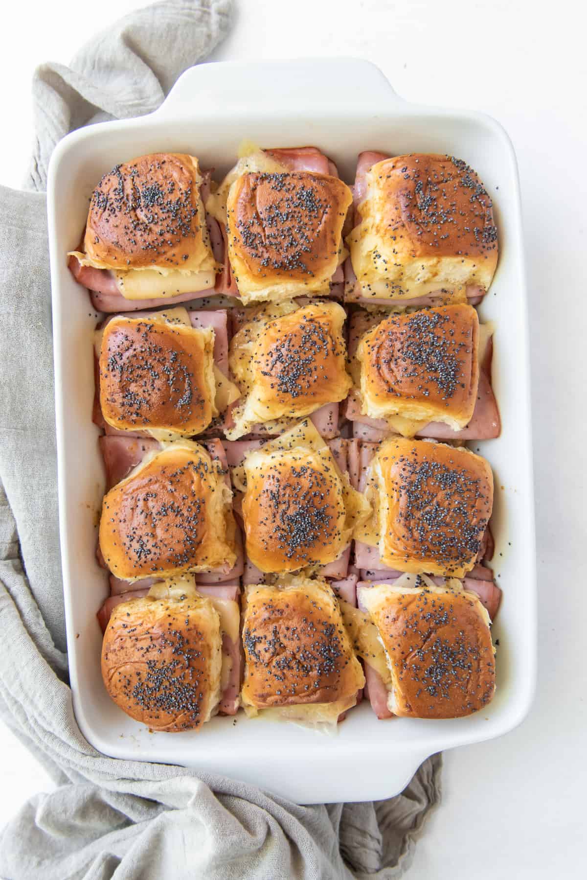 A top down shot of a baking dish full of ham and cheese sliders.