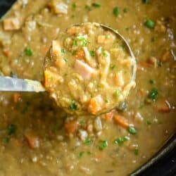 A ladle scooping split pea soup from a slow cooker.