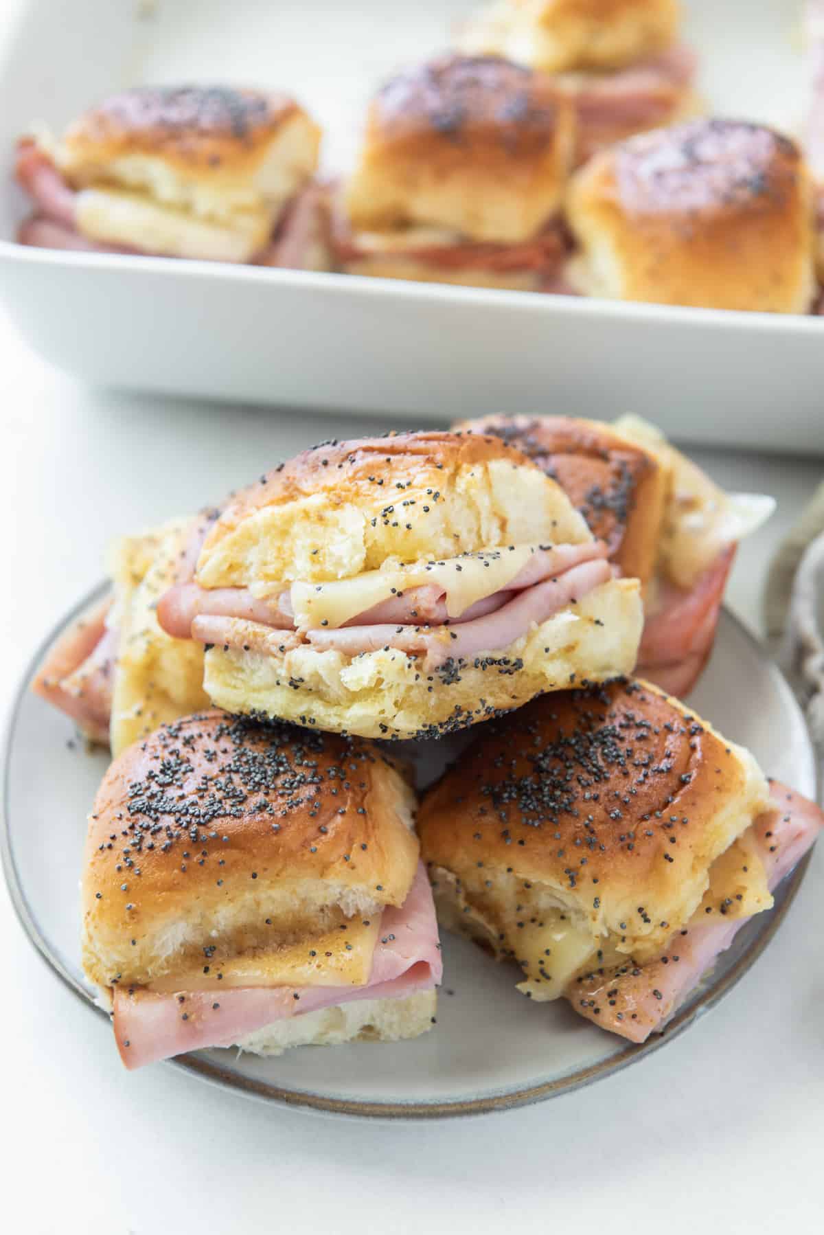Ham and cheese sliders stacked on a white plate.