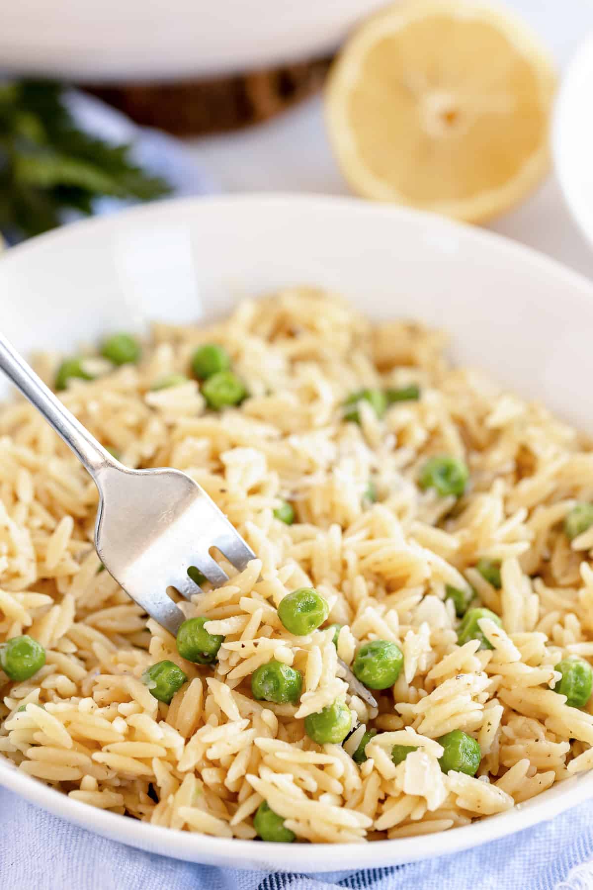 A fork in a bowl of orzo and peas.