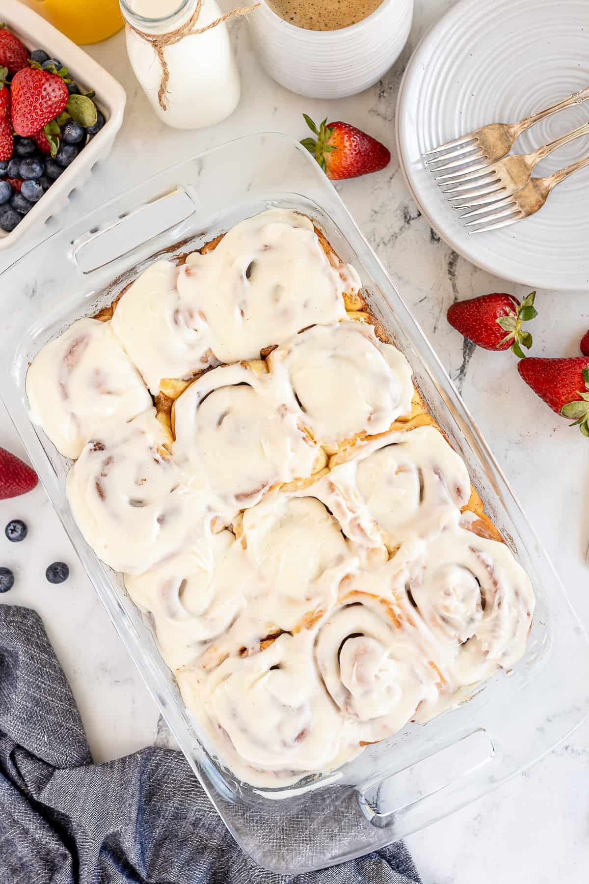 A top down shot of a baking pan full of frosted cinnamon rolls.