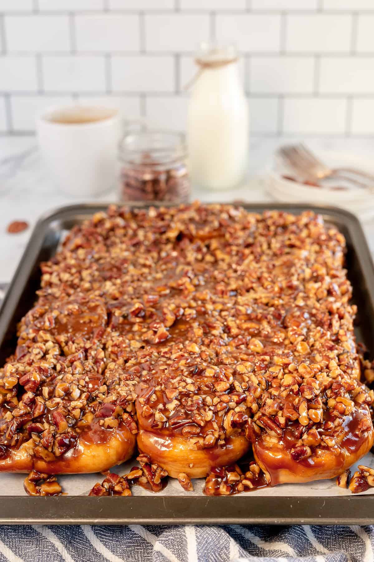 Pecan Sticky Buns on a baking sheet on a kitchen counter.