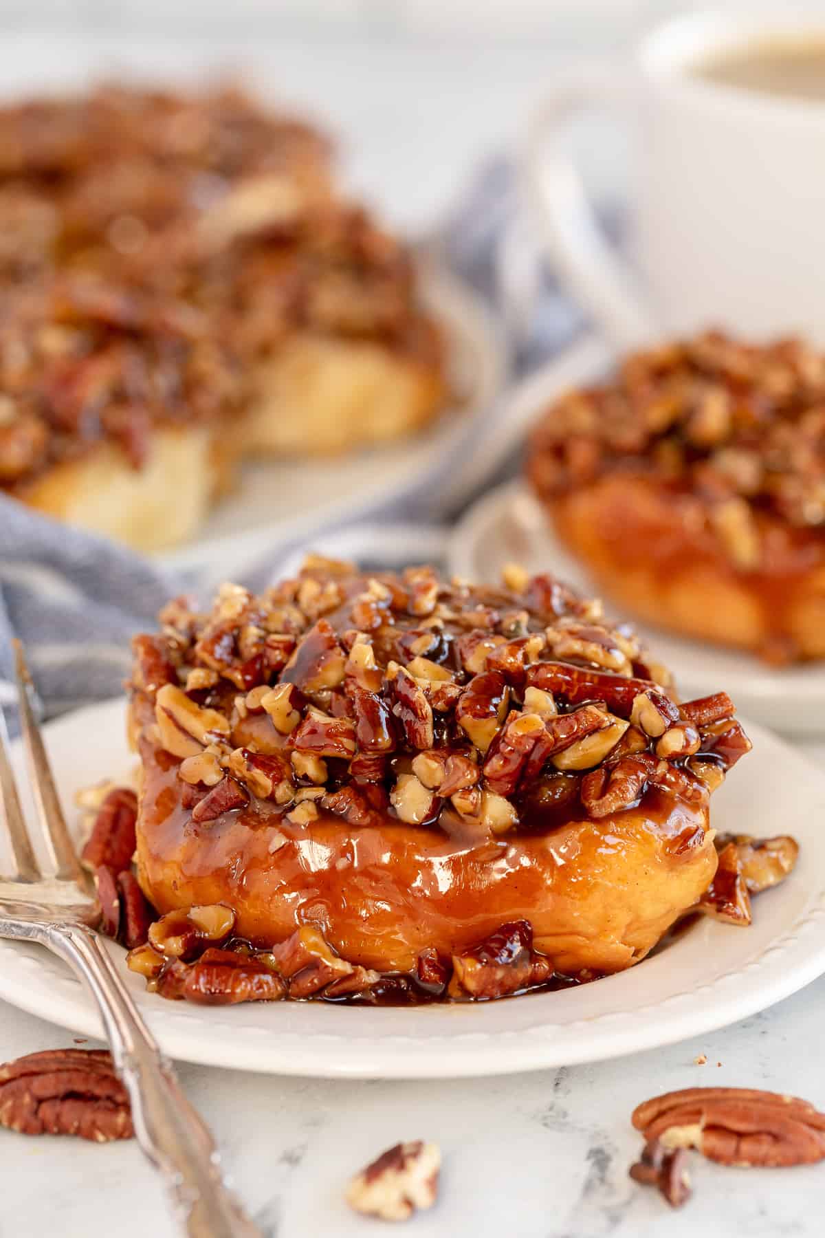 A Pecan Sticky Bun on a white plate with a fork.