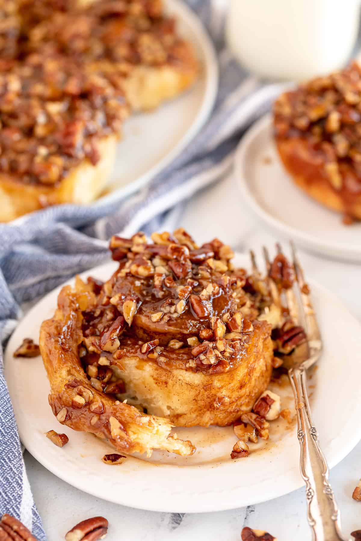 A Pecan Sticky Bun on a white plate with a fork.