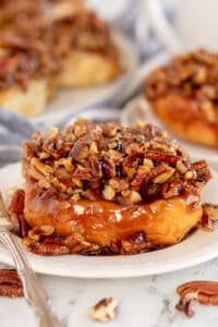 A sticky bun on a plate with a fork.