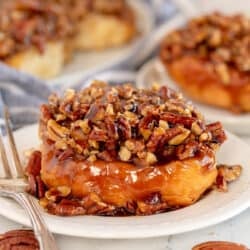 A sticky bun on a plate with a fork.