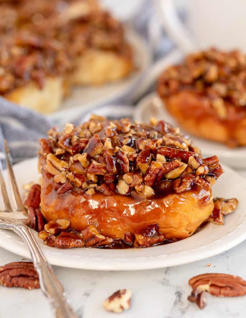 A sticky bun on a plate with a fork.