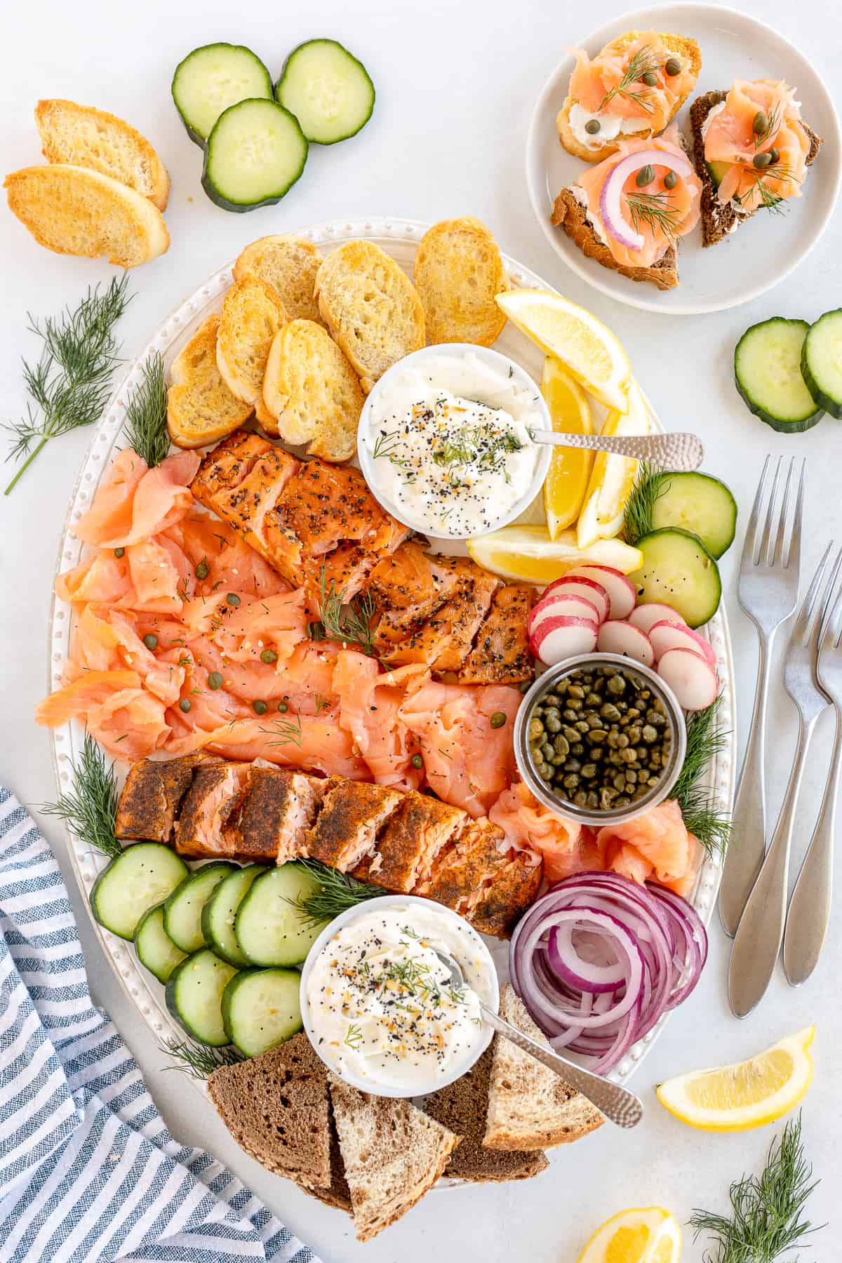 A top down shot of a smoked salmon platter with crostini and cream cheese spread.