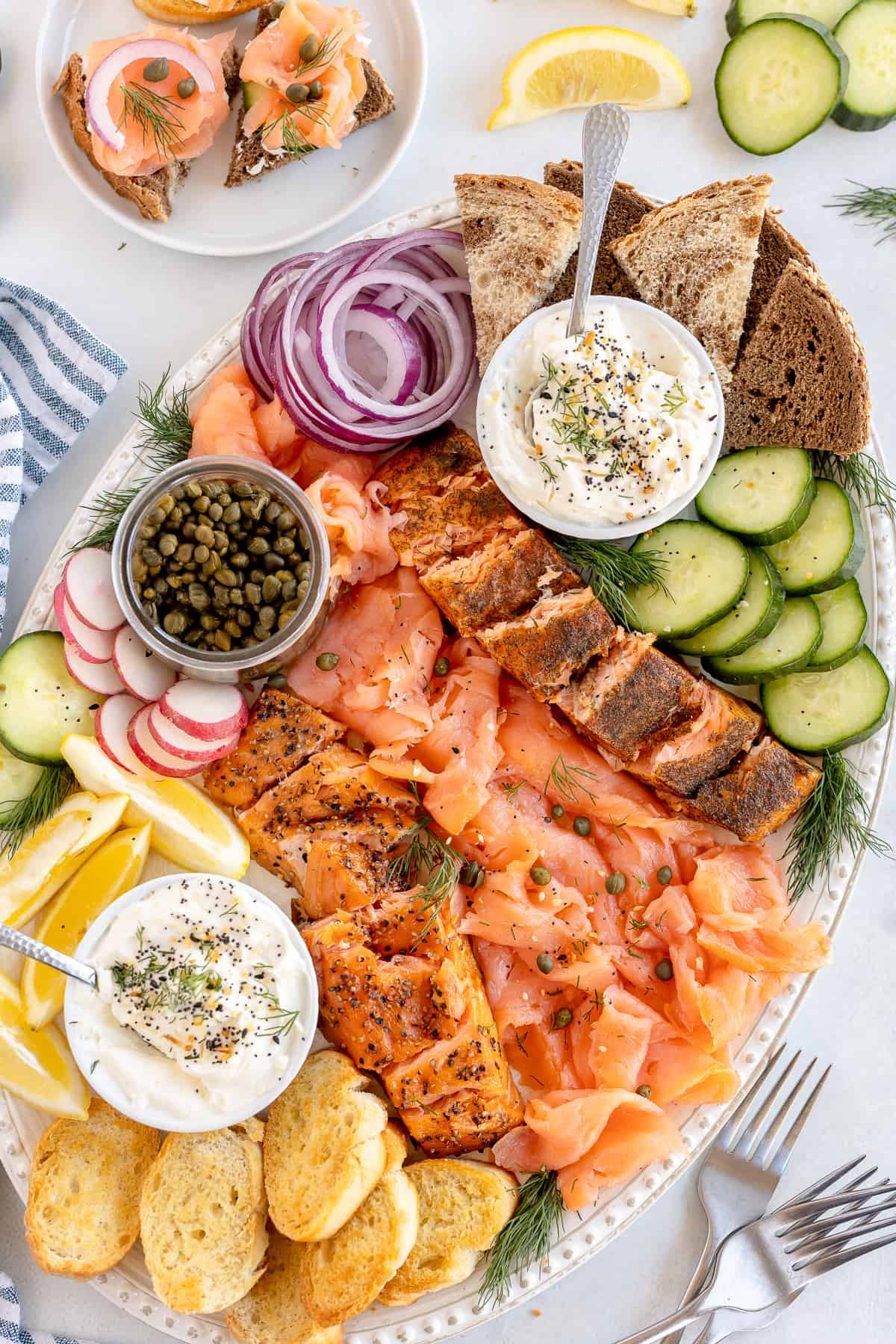 A platter filled with smoked salmon, crostini, and vegeatbles.