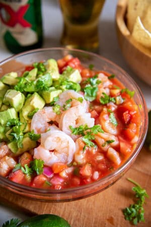 Mexican Shrimp Cocktail with avocado in a serving bowl on a board.