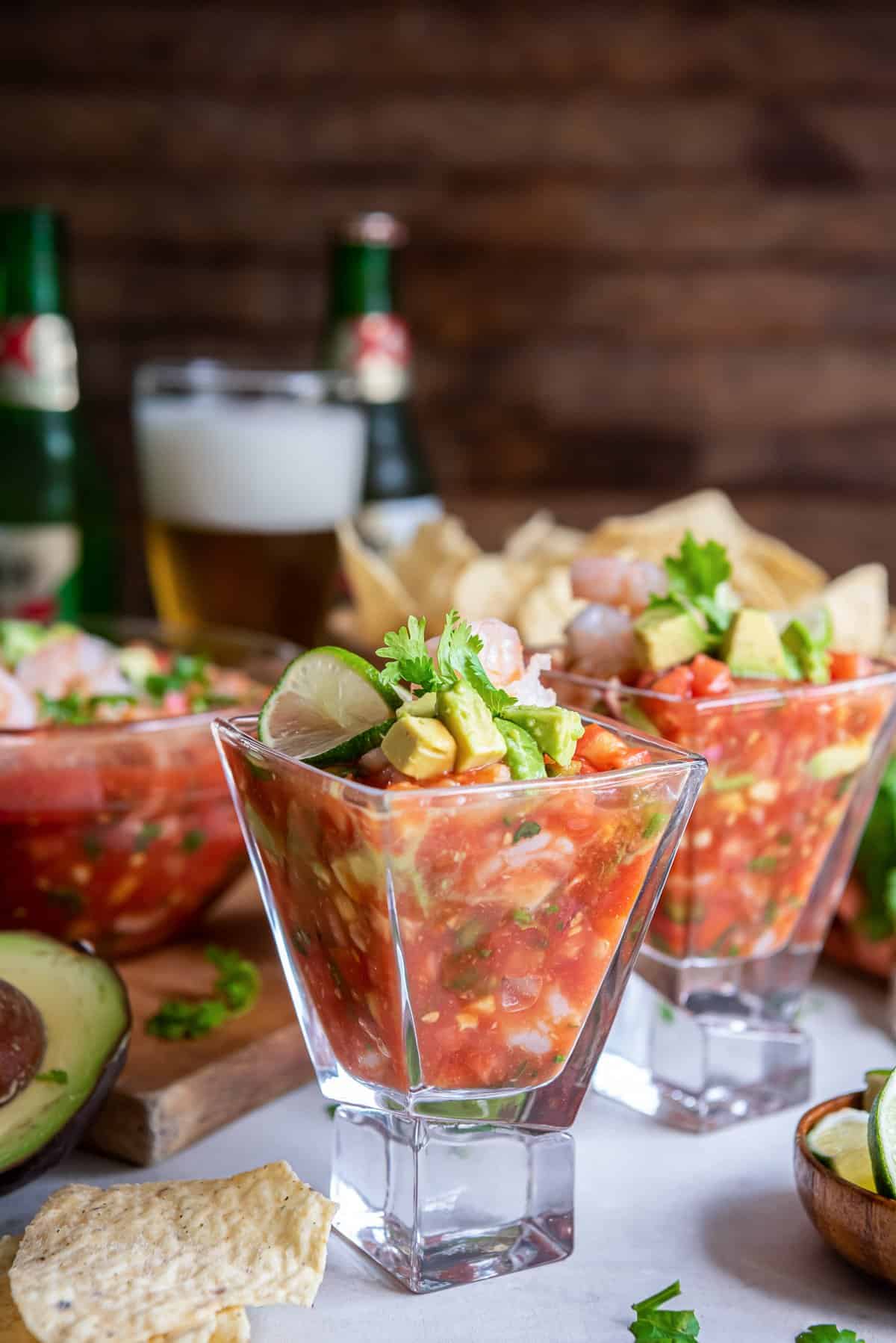 Mexican Shrimp Cocktail in a margarita glass with beer and tortilla chips in the background.