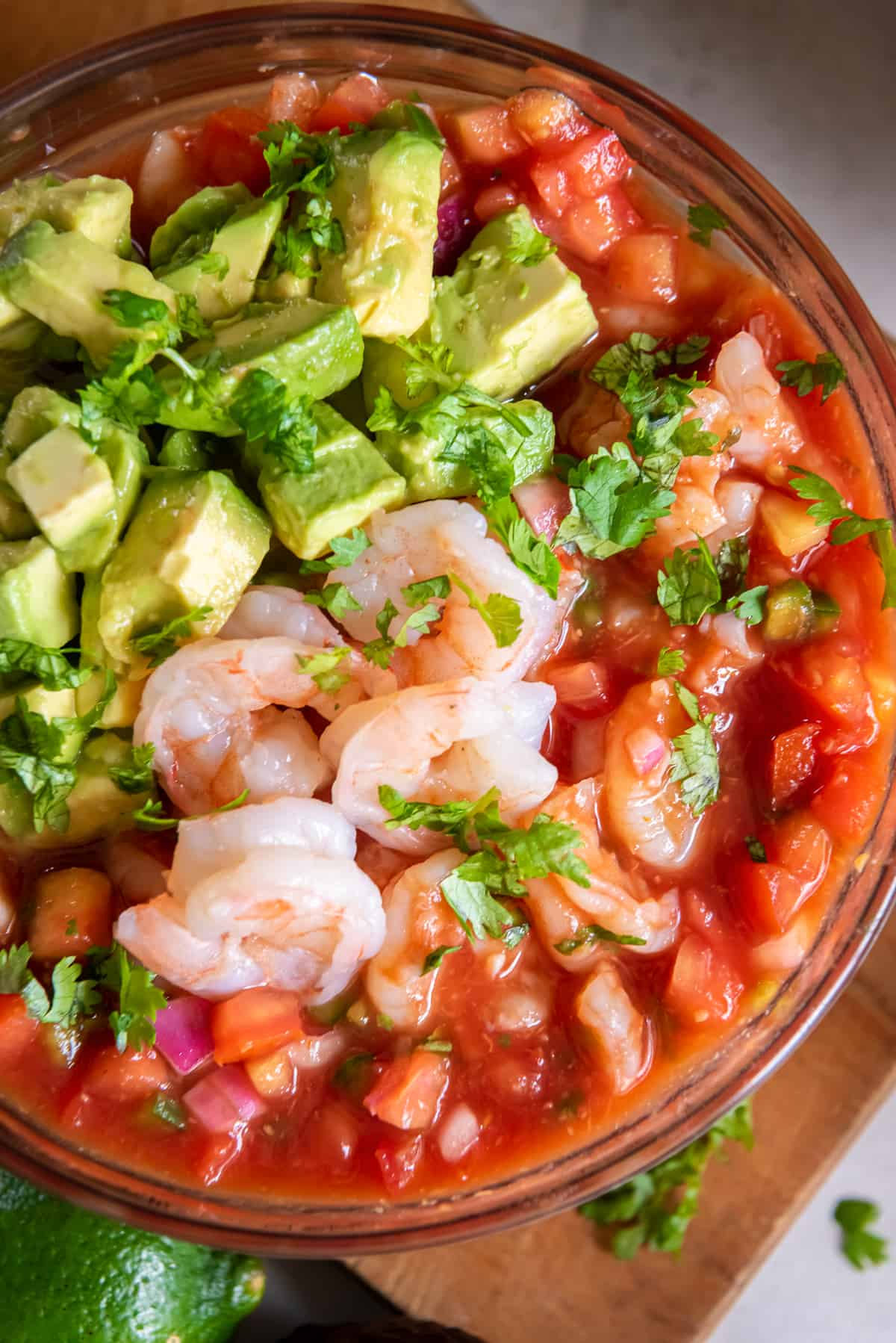 A top down shot of shrimp and avocado in cocktail sauce.