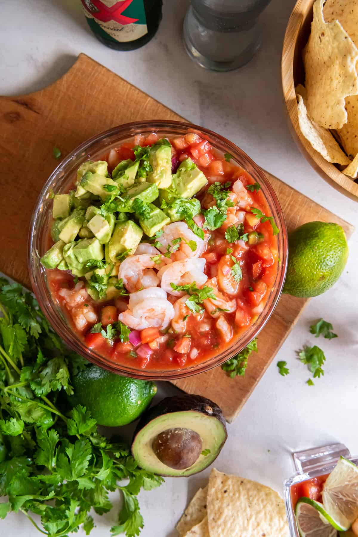 A bowl of Mexican Shrimp Cocktail on a board with cilantro and avocado.