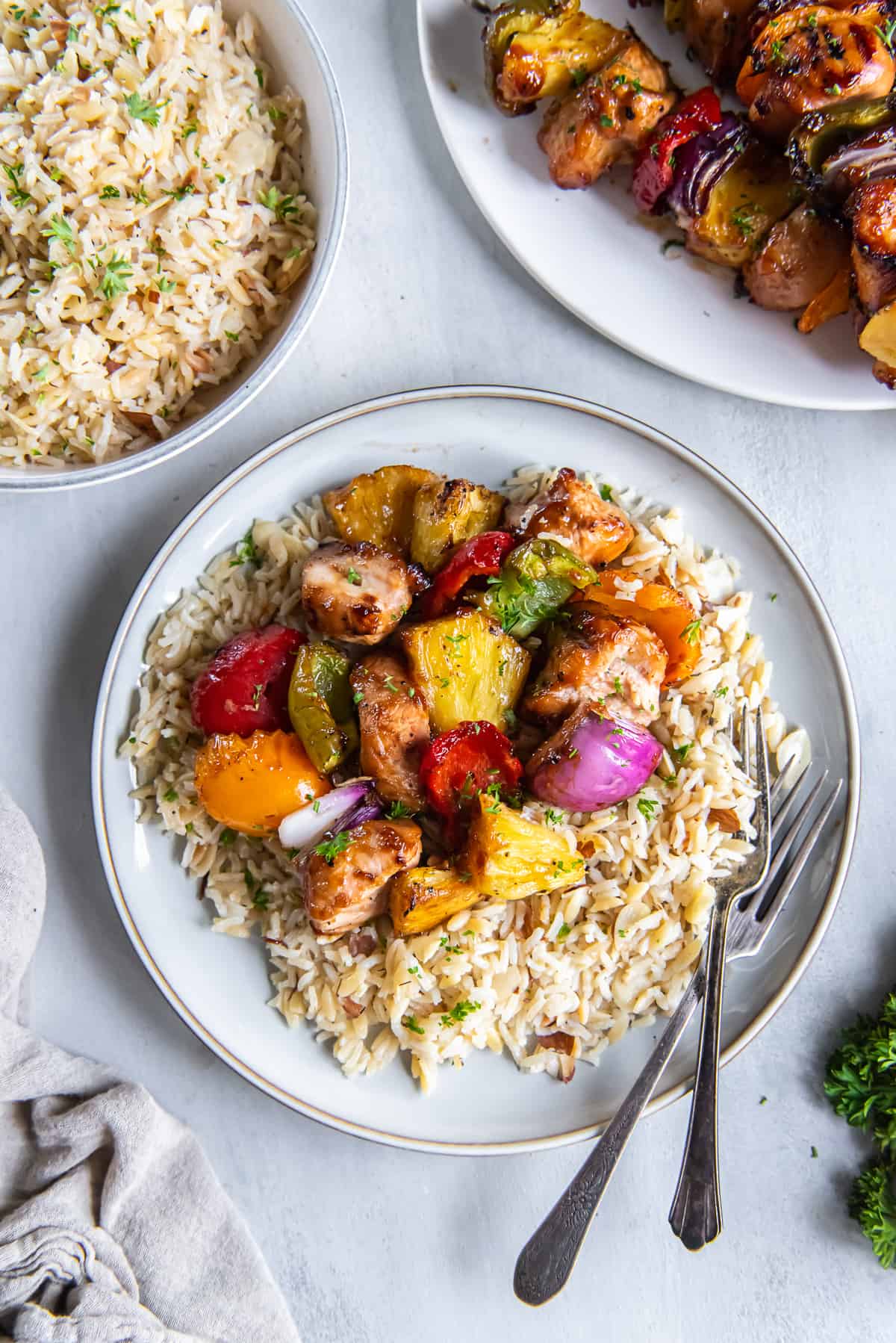 Chicken pineapple and peppers on rice on a white plate.