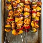 Pineapple chicken skewers on a baking sheet.