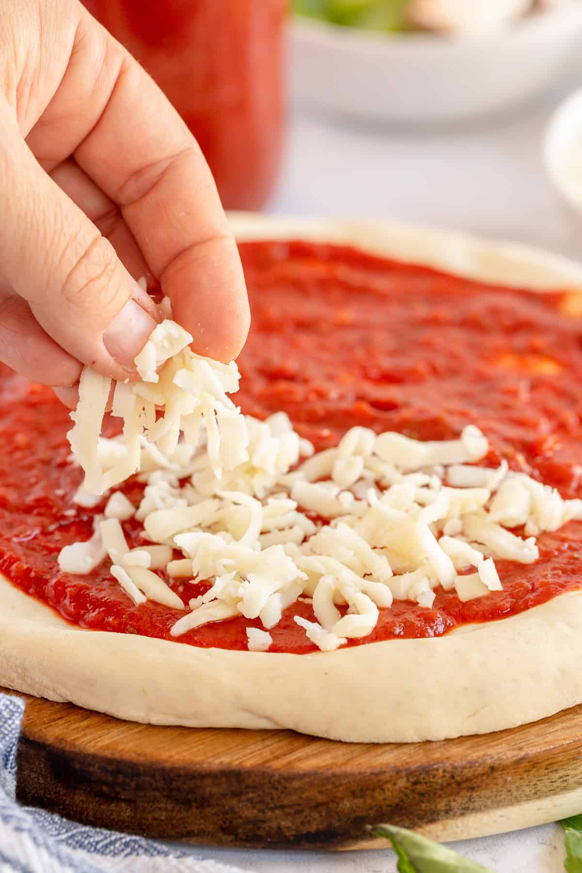 A hand sprinkling cheese on a pizza.