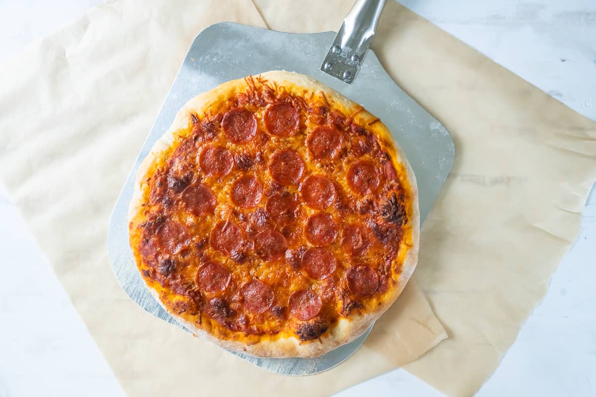 A top down shot of a pepperoni pizza on a pizza peel.